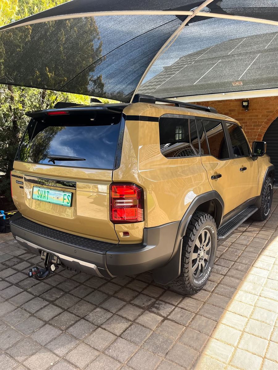 Tan Toyota Land Cruiser Prado with glossy paint under a carport